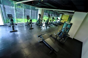 Un gimnasio con equipo de ejercicio, ventanas amplias y suelo de hormigón.