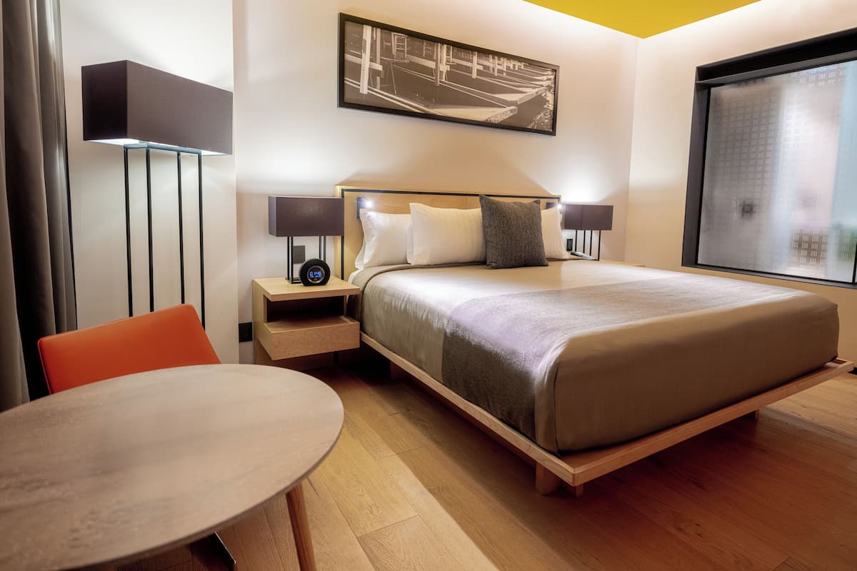 Une chambre d’hôtel moderne équipée d’un lit, de tables de chevet, d’un bureau et d’une chaise.