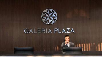 A reception desk with a logo above it and the name 'GALERIA PLAZA' on the wall.