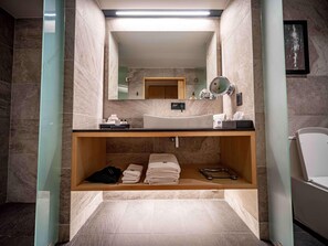A modern bathroom with a large mirror, a sink, and a shelf with towels and toiletries.