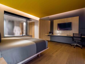 A modern bedroom with a bed, a desk, and a TV.