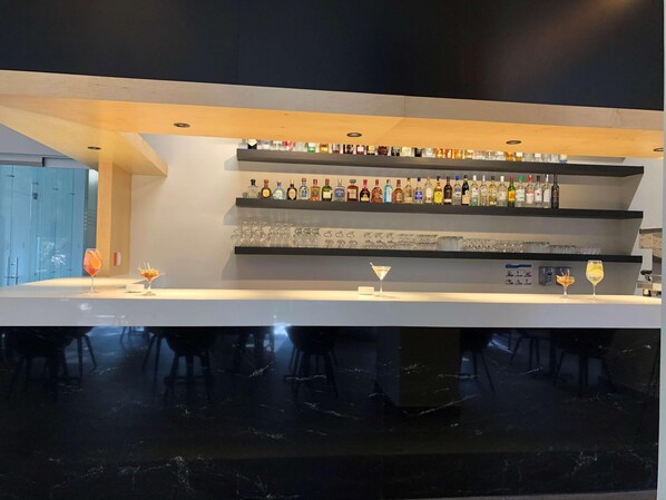 A modern bar area with multiple shelves of liquor bottles and glasses. - Galeria Plaza San Jeronimo (Mexico City)