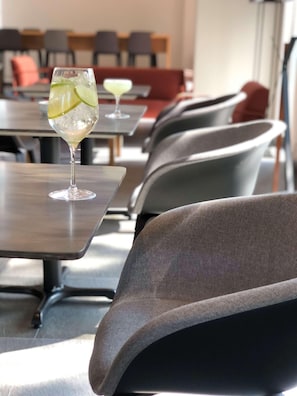 A restaurant with tables and chairs, a glass of cocktail with lime, and another glass with a green drink. - Galeria Plaza San Jeronimo (Mexico City)