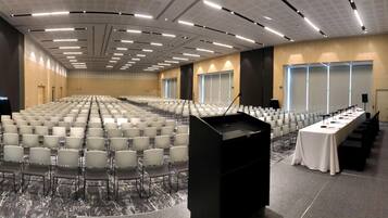 A large conference room with rows of chairs, a podium, and a table with chairs.