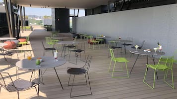 An outdoor patio area with round tables and chairs, some with drinks and snacks.