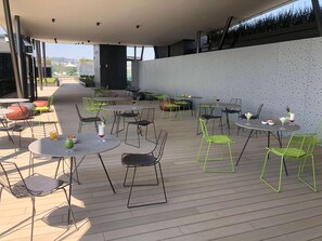 An outdoor patio area with round tables and chairs, some with drinks and snacks. - Galeria Plaza San Jeronimo (Mexico City)