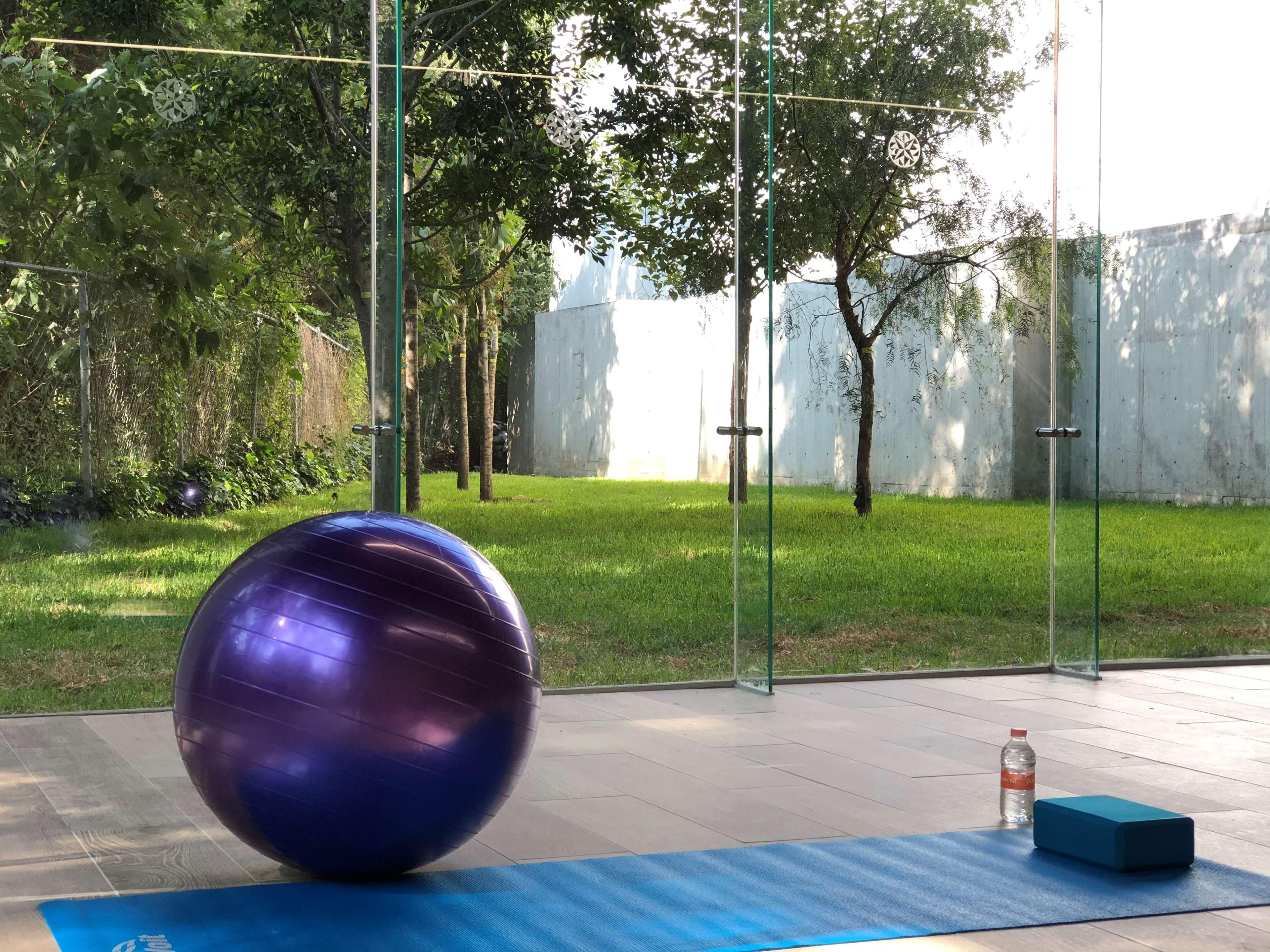 A gym area with exercise equipment, a blue mat, and a water bottle.