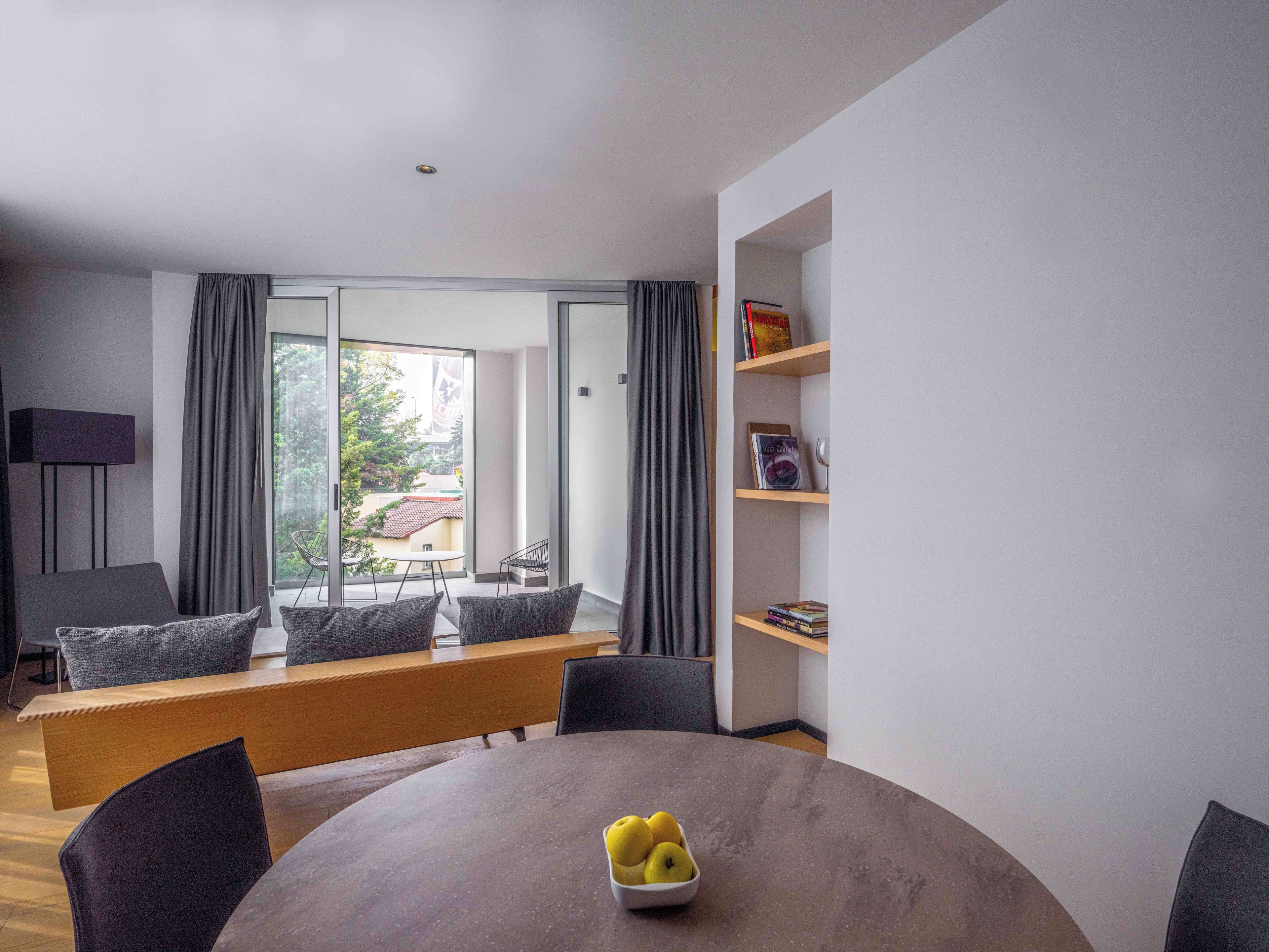 A modern living room with a round table, a bench, and a bookshelf.
