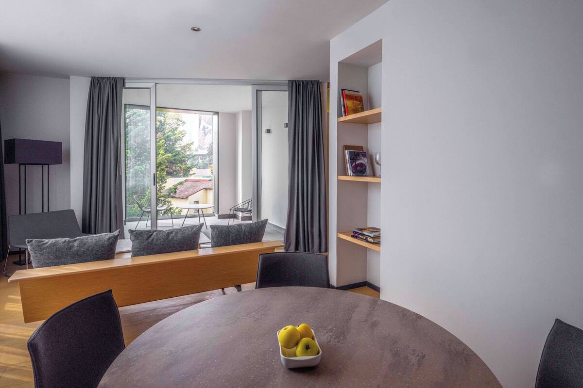 Un salon moderne avec une table ronde, un banc et une bibliothèque.