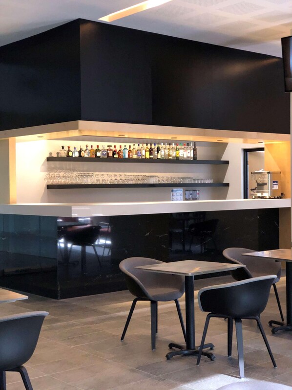 A modern bar area with a black countertop, shelves of liquor bottles, and several bar stools. - Galeria Plaza San Jeronimo (Mexico City)