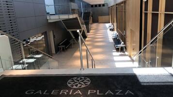 A modern interior with a central staircase, glass railings, and seating areas.