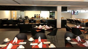 A modern dining area with black chairs and tables, a buffet with various food items, and a television screen on the wall. - Galeria Plaza San Jeronimo (Mexico City)