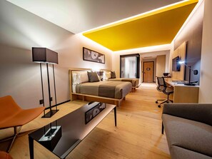 Una habitación de hotel moderna con una cama, dos mesitas de noche, un escritorio, una silla y un televisor.