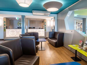A hotel lobby with leather seating, a reception desk, and a visible kitchen area. - B&B Hotel Erlangen (Erlangen)