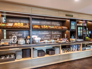 Een ontbijtbuffet met verschillende soorten eten en een koffieapparaat.
