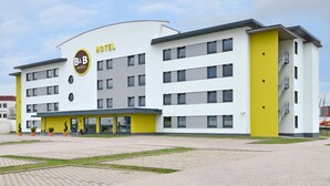 A modern hotel with a yellow and white facade, multiple floors, and a covered entrance area. - B&B Hotel Erlangen (Erlangen)