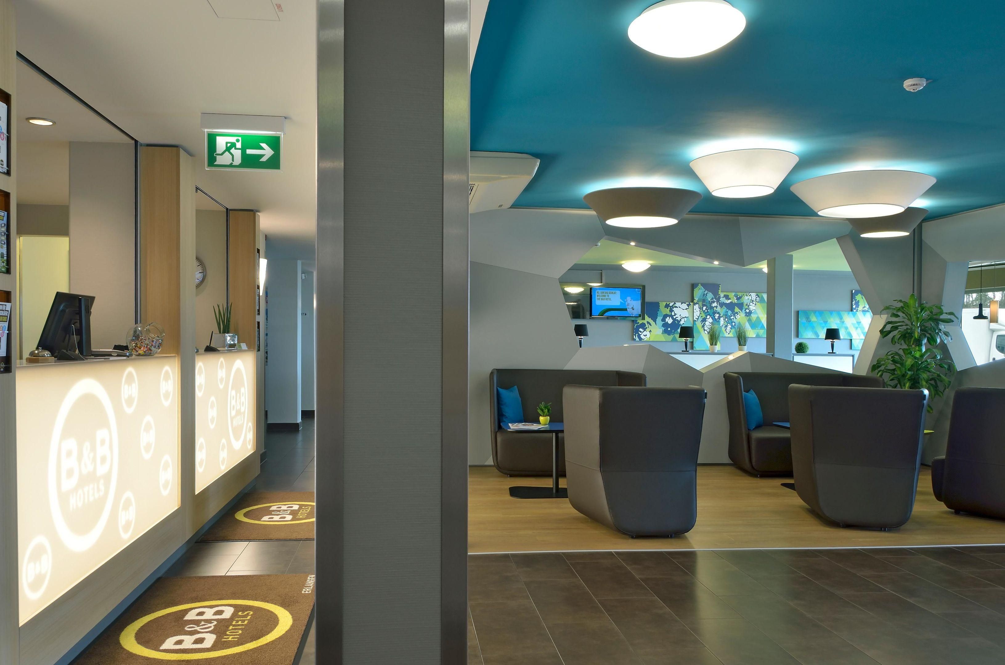 A hotel reception area with a modern design, including a reception desk, seating area, and a blue ceiling with recessed lighting.