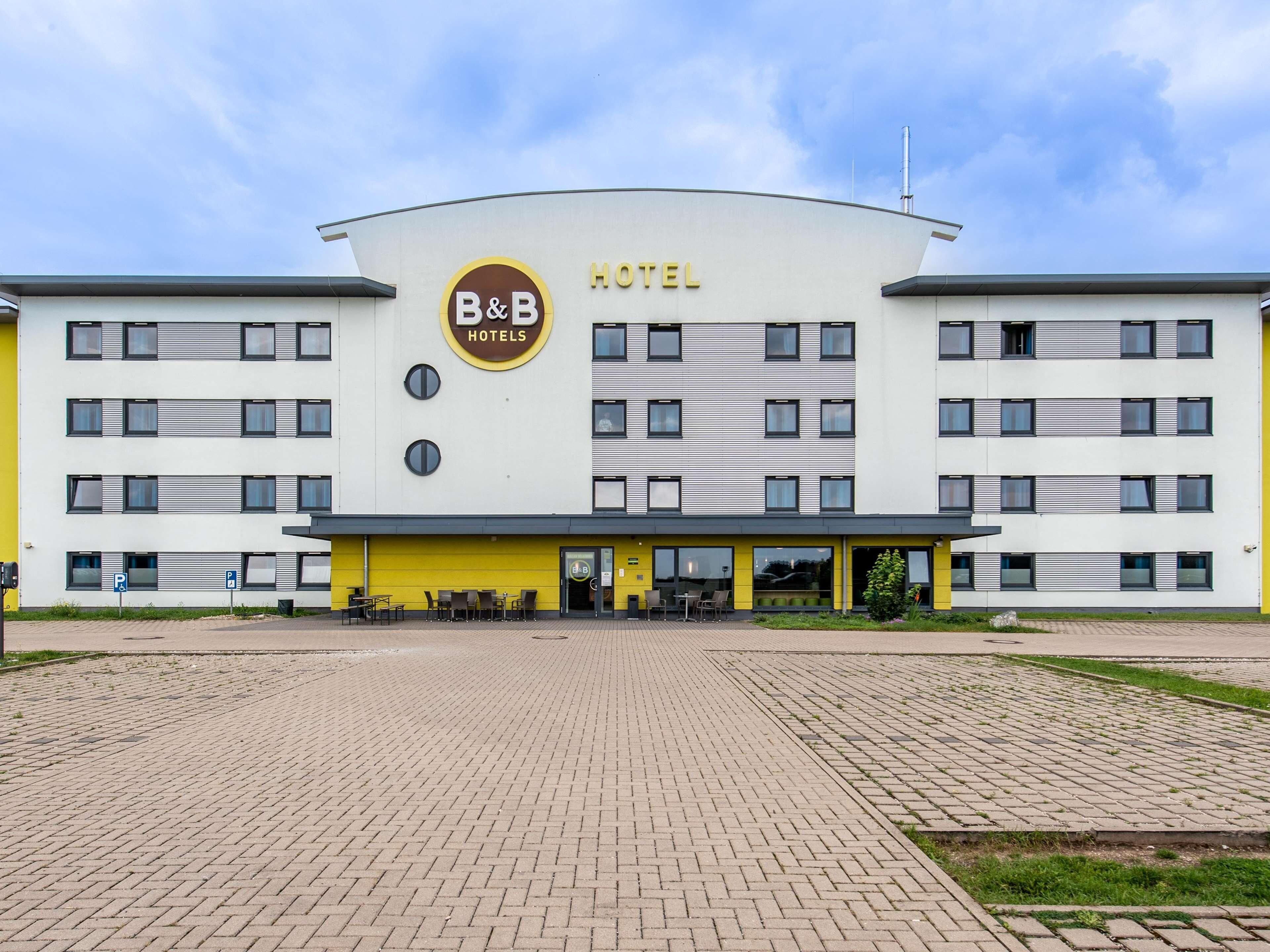 A B&B hotel with a modern design, featuring a prominent logo and a yellow facade.