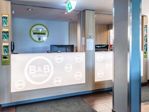 A B&B hotel reception desk with a digital screen, a phone, and a sign with the hotel's name. - B&B Hotel Erlangen (Erlangen)