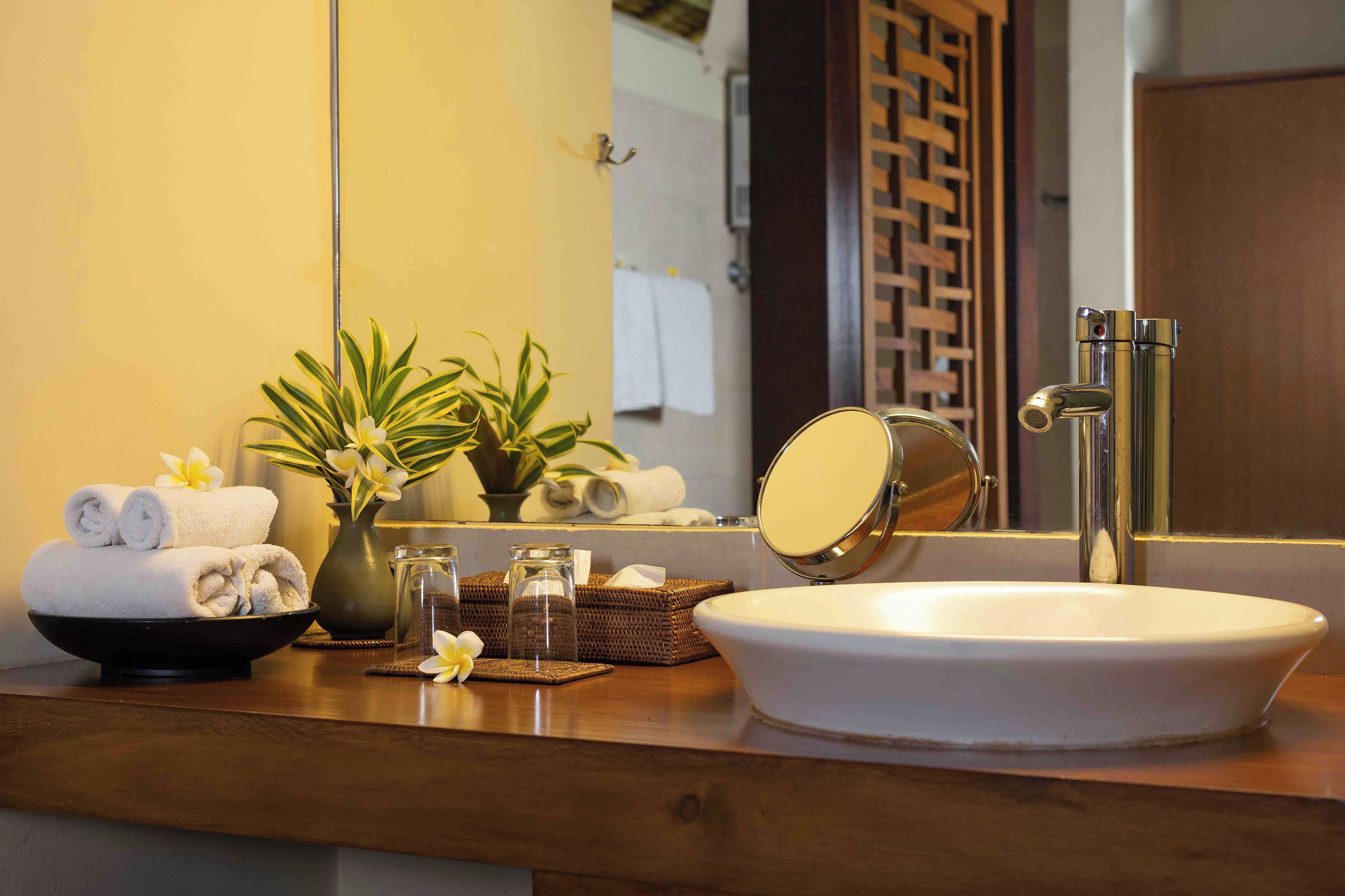 A bathroom vanity with a white sink, a mirror, and toiletries.