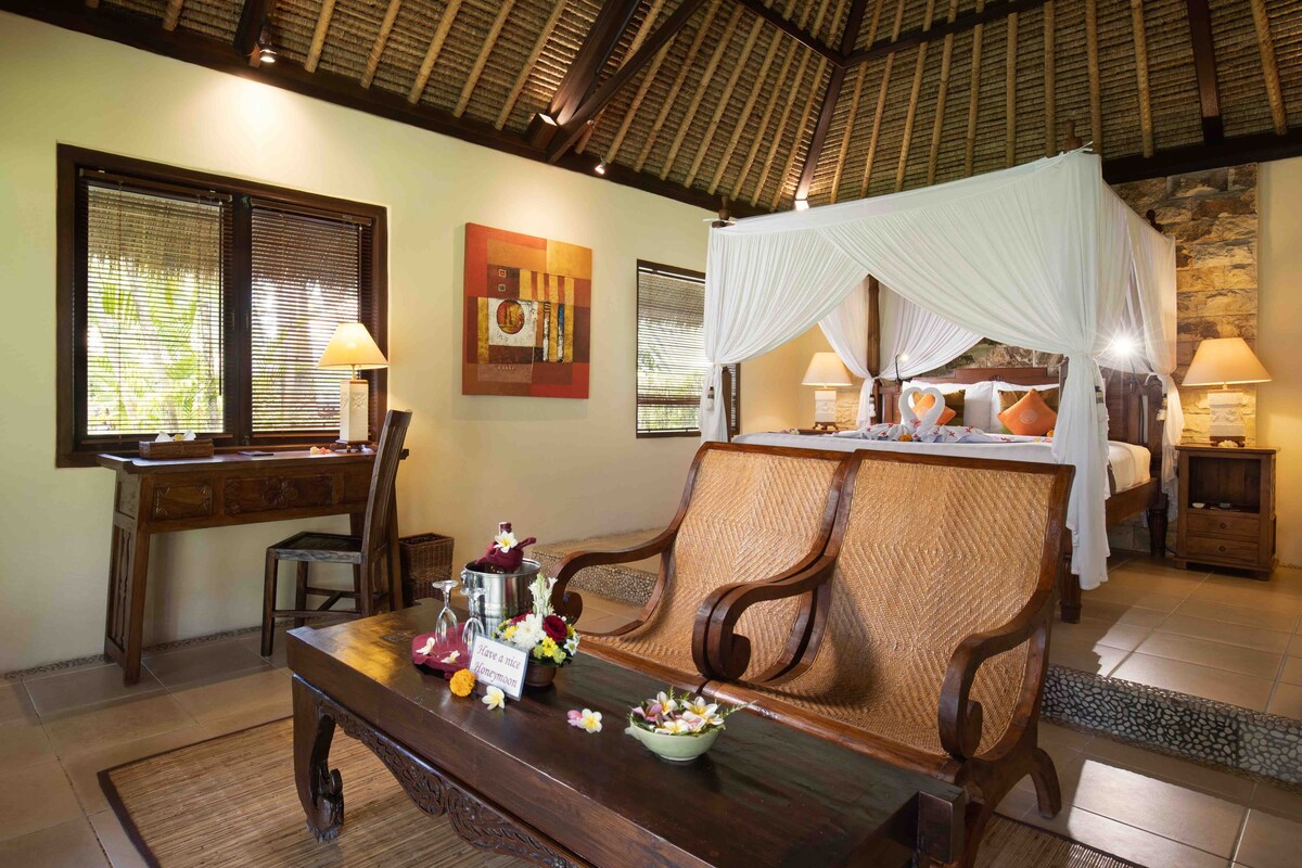 A room with a bed, a wooden desk, and a bench.