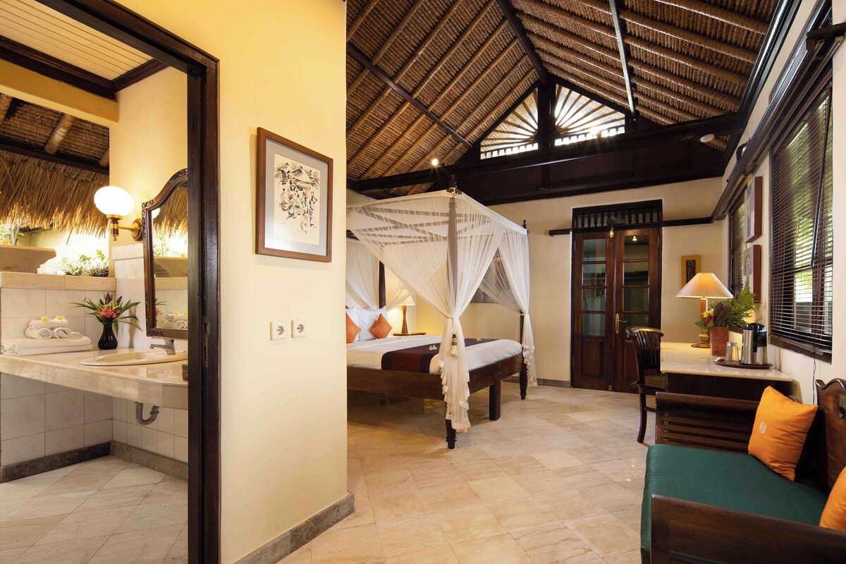 A hotel room with a bed, a sitting area, and a bathroom.