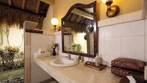 A bathroom with a large mirror, white sink, and a towel rack. - Alam Anda Ocean Front Resort & Spa (Tejakula)