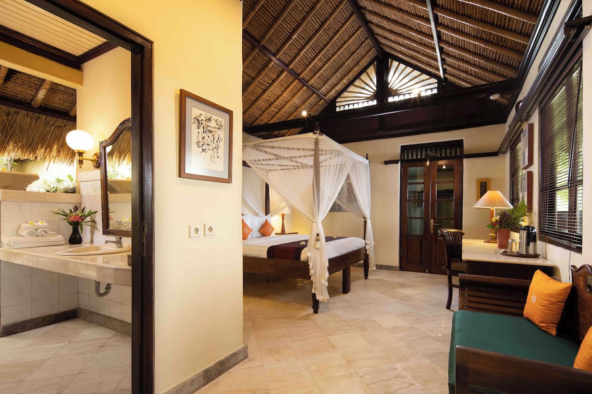 A hotel room with a bed, a sitting area, and a bathroom.