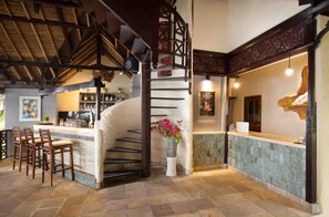 A bar area with a stone counter, wooden chairs, and a staircase with a decorative railing. - Alam Anda Ocean Front Resort & Spa (Tejakula)