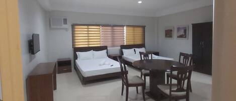A spacious room with a large dining table and chairs, a sofa, and a bed.