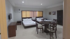 A spacious room with a large dining table and chairs, a sofa, and a bed. - OYO 881 Nest Suites (Quezon City)