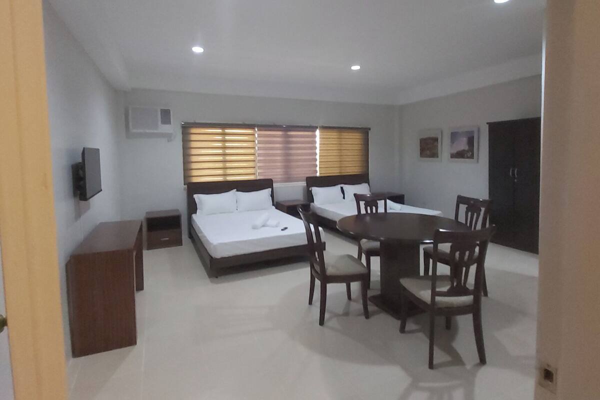 Una habitación amplia con una gran mesa de comedor y sillas, un sofá y una cama.