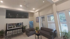 A spacious living room with a large flat-screen TV, two grey sofas, a coffee table, and several potted plants. - OYO 881 Nest Suites (Quezon City)