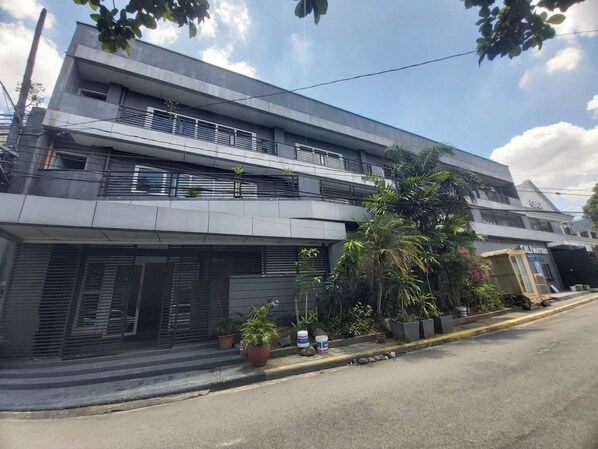 A modern two-story building with balconies, potted plants, and a visible entrance. - OYO 881 Nest Suites (Quezon City)
