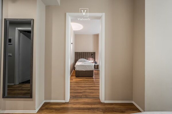 A hallway leading to a bedroom with a bed, bedside table, and a nightstand. - Vh Eurostar Tirana Hotel Congress & Spa (Tirana)