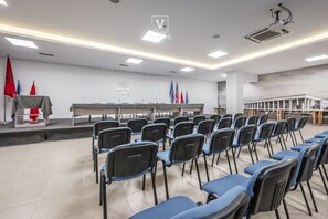 Ein Konferenzraum mit Stuhlreihen, einem Rednerpult und Flaggen.