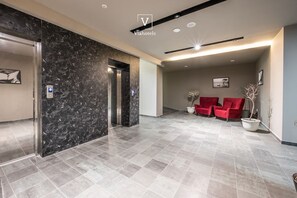 A modern lobby with a marble wall, a reception desk, and red seating. - Vh Eurostar Tirana Hotel Congress & Spa (Tirana)