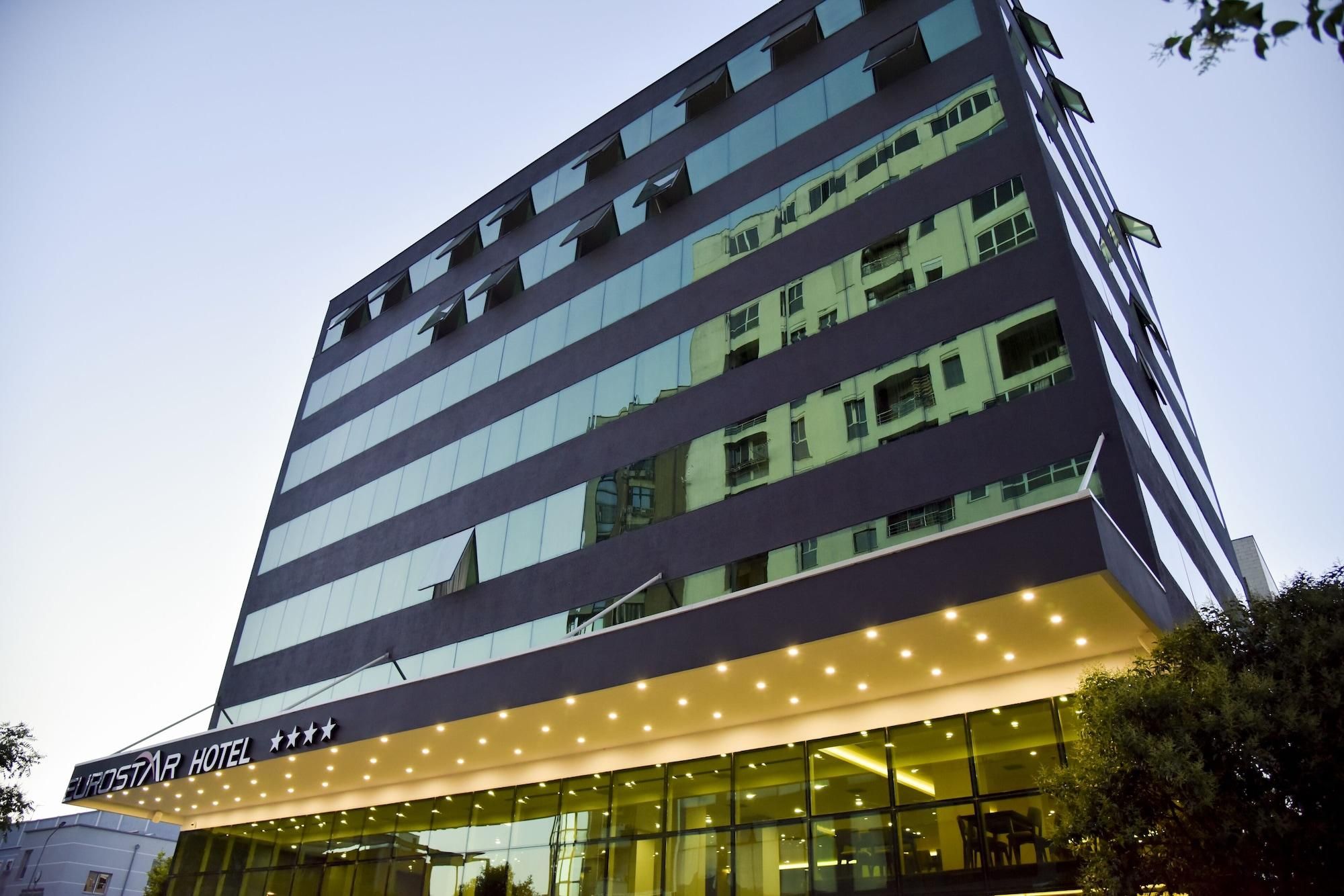 A multi-story hotel with a modern facade, large windows, and a well-lit entrance.