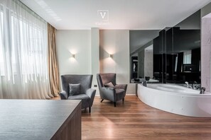 Moderni kylpyhuone, jossa on erillinen kylpyamme, kaksi nojatuolia ja suuri peili.