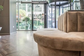 A modern lobby with a plush beige sofa, a glass entrance, and a view of the outside. - Vh Eurostar Tirana Hotel Congress & Spa (Tirana)