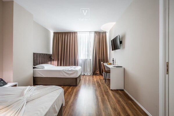 A hotel room with a bed, a desk, a chair, a TV mounted on the wall, and a window with curtains. - Vh Eurostar Tirana Hotel Congress & Spa (Tirana)