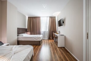 A hotel room with a bed, a desk, a chair, a TV mounted on the wall, and a window with curtains. - Vh Eurostar Tirana Hotel Congress & Spa (Tirana)
