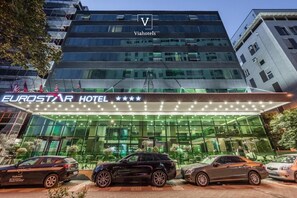 L’hôtel Eurostar se distingue par sa façade moderne en verre, son panneau lumineux et son parking où sont stationnées plusieurs voitures.