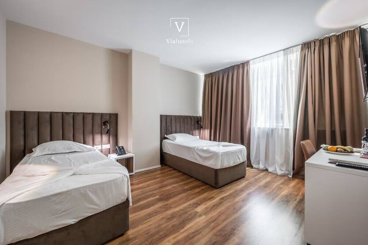 A hotel room with two beds, a desk, and a chair.