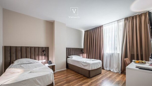 Ein Hotelzimmer mit zwei Betten, einem Schreibtisch und einem Stuhl.
