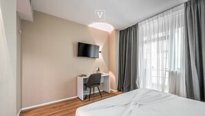 A hotel room with a bed, a desk, a chair, a TV mounted on the wall, and a window with curtains. - Vh Eurostar Tirana Hotel Congress & Spa (Tirana)
