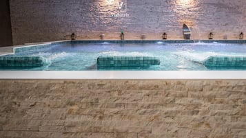 Una vasca idromassaggio con una parete in pietra e il logo di Viahotels.