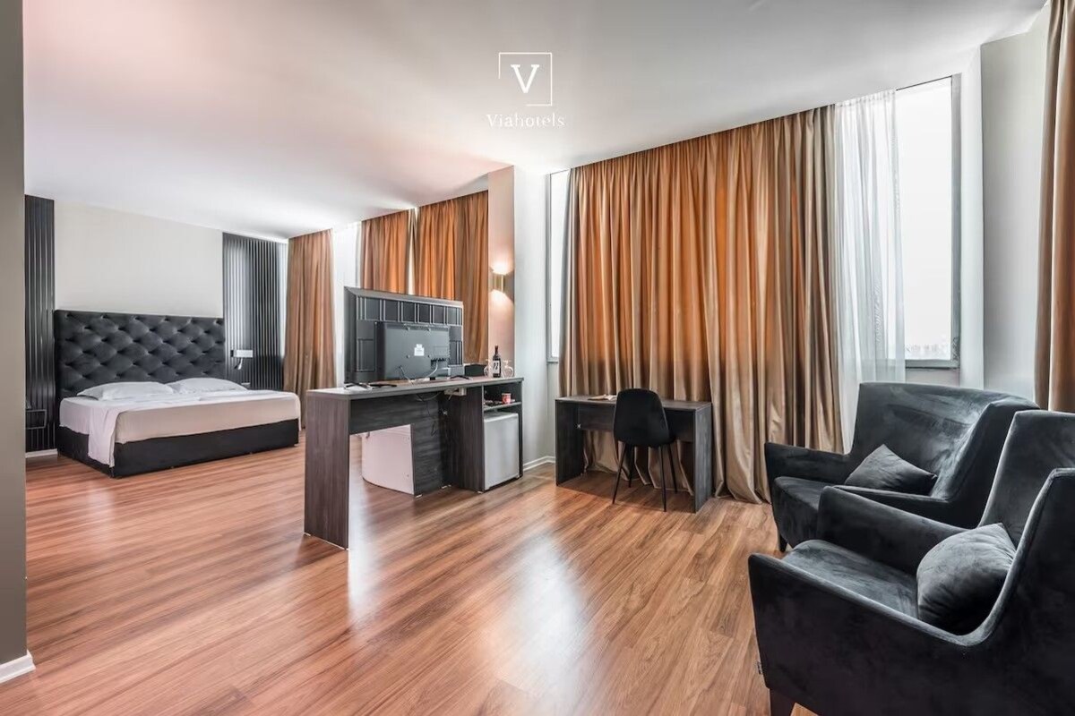 A modern hotel room with a bed, desk, and seating area.