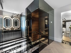 Et moderne interiør med et marmorgulv, en glas elevator og et receptionsområde med oplyste spejle.
