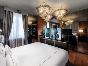 A modern hotel room with a large bed, a TV, and decorative chandeliers. - The Plein Hotel (Milan)